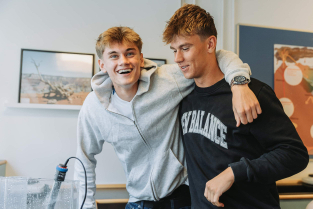 To elever griner sammen i klasselokalet